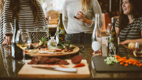 Women standing up talking at a dinner party